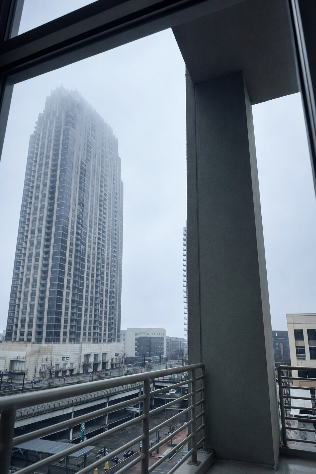 The city looks distant and calm, like it’s being watched from a private moment indoors. Frame within a frame uses the window edges to hold the skyline in place and keep the viewer focused on the atmosphere outside.